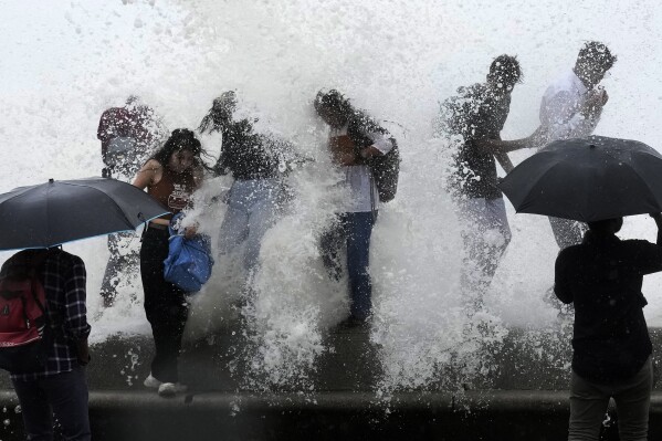 People enjoy high tide waves on the coast of the Arabian Sea in Mumbai, India, Thursday, July 6, 2023. (AP Photo/Rajanish Kakade)