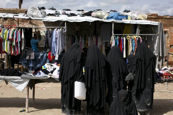 In this March 31, 2019, photo, women shop the marketplace at al-Hol camp in Hasakeh province, Syria. Security conditions in the al-Hol camp that is home to tens of thousands of wives and children of Islamic State group fighters has been bad for the past months and will likely get worse now that Turkey is on the offensive in northern Syria. The camp that is home to more than 70,000 has witnessed crimes carried out by IS women against residents whom they consider apostates. (AP Photo/Maya Alleruzzo)
