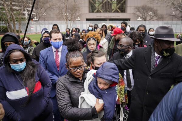Chyna Whitaker, center, holds her son Daunte Jr., as she walks up to microphones to speak during a news conference, Tuesday, April 13, 2021, in Minneapolis. The father, Daunte Wright, 20, was shot and killed by police Sunday after a traffic stop in Brooklyn Center, Minn. (AP Photo/John Minchillo)