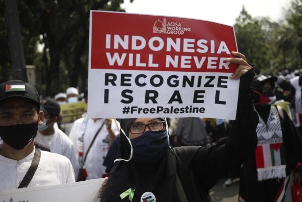 A Muslim woman holds up a poster during a rally against Israel's attacks on Gaza, outside the U.S. Embassy in Jakarta, Indonesia, Friday, May 21, 2021. (AP Photo/Dita Alangkara)