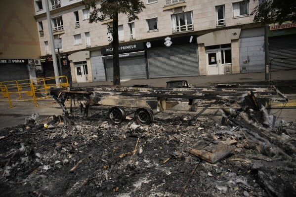 A charred vehicle is pictured Wednesday, June 28, 2023 in Nanterre, outside Paris. France's government announced heightened police presence around Paris and other big cities and called for calm after scattered violence erupted over the death of a 17-year-old delivery driver who was shot and killed Tuesday June 27, 2023 during a police check. (AP Photo/Lewis Joly)