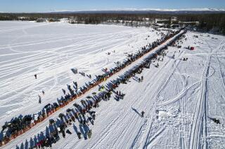 FILE - A competitor mushes across Willow Lake during the restart of the Iditarod Trail Sled Dog Race on March 6, 2022, in Willow, Alaska. Two back-of-the-pack mushers had to be rescued in separate incidents from race Friday, March 18, after winds from a severe ground storm caused deteriorating conditions, race officials said. (Loren Holmes/Anchorage Daily News via AP, File)