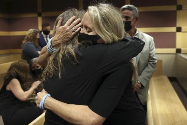 CORRECTS SPELLING OF FIRST NAME TO DEBBI, NOT DEBBIE- Gena Hoyer, right, hugs Debbi Hixon during a court recess following Marjory Stoneman Douglas High School shooter Nikolas Cruz's guilty plea on all 17 counts of premeditated murder and 17 counts of attempted murder in the 2018 shootings, Wednesday, Oct. 20, 2021, at the Broward County Courthouse in Fort Lauderdale, Fla. Hoyer's son, Luke Hoyer, 15, and Hixon's husband, Christopher Hixon, 49, were both killed in the massacre. (Amy Beth Bennett/South Florida Sun Sentinel via AP, Pool)