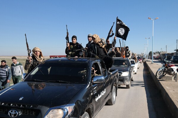 In this file photo released on May 4, 2015, by a militant website, which has been verified and is consistent with other AP reporting, Islamic State militants drive in a convoy through Tel Abyad, northeast Syria. (Militant website via AP, File)