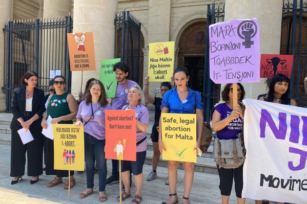 FILE - Activists hold up banners in both English and Maltese reading, 'I decide', 'Abortion is a woman's right', and 'Abortion is healthcare, not a crime', as they stand outside the Maltese law courts in Valletta, Malta, Wednesday, June 15, 2022. Maltese lawmakers are expected to vote Wednesday, June 28, 2023 on landmark legislation to ease the the strictest abortion laws in the European Union. But a coalition of pro-choice campaigners say last-minute changes make the legislation “vague, unworkable and even dangerous.” (AP Photo/Kevin Schembri Orland, File)
