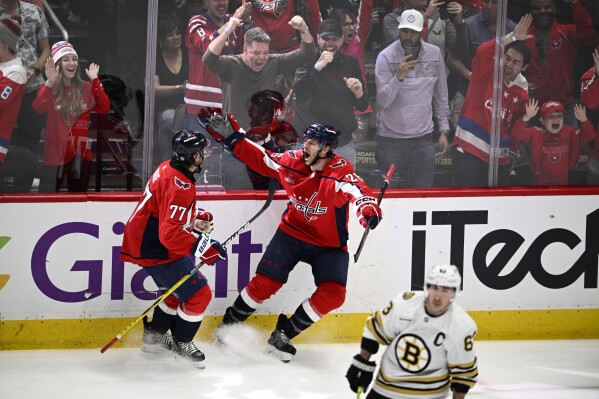 Washington Capitals center Nic Dowd (26) celebrates his goal with T.J. Oshie (77) during the third period of an NHL hockey game as Boston Bruins left wing Brad Marchand (63) skates away, Monday, April 15, 2024, in Washington. The Capitals won 2-0. (AP Photo/Nick Wass)