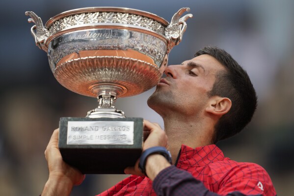 FILE - Serbia's Novak Djokovic kisses the trophy as he celebrates winning the men's singles final match of the French Open tennis tournament against Norway's Casper Ruud at Roland Garros stadium in Paris, Sunday, June 11, 2023. Djokovic won three of his men’s-record 24 Grand Slam titles at the French Open, which starts Sunday at Roland Garros in Paris. (AP Photo/Christophe Ena, File)