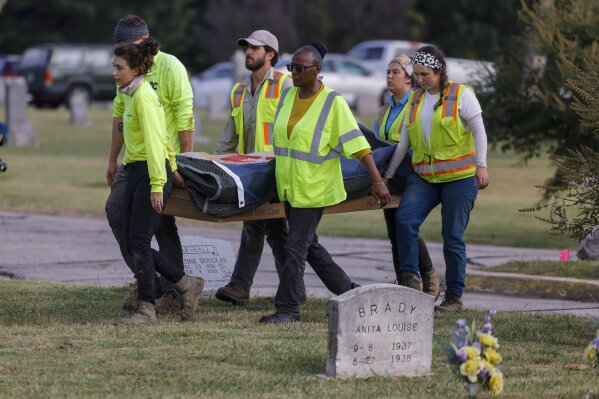 Researchers and burial oversight committee member Brenda Alford carry the first set of remains exhumed from the latest dig site in Oaklawn Cemetery to an onsite lab for further examination Wednesday, Sept. 13, 2023 in Tulsa, Okla. They are searching for vicims of the 1921 Tulsa Race Massacre. (Mike Simons /Tulsa World via AP)
