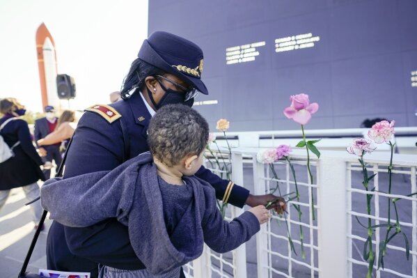 Retired Army Colonel Cynthia Watkins places a flower at the Space Mirror Memorial during a ceremony to honor fallen astronauts at the at the Kennedy Space Center Visitors Complex, Thursday, Jan. 28, 2021, in Cape Canaveral, Fla. (AP Photo/John Raoux)