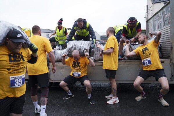A contestant loads a 50kg bag of coal onto his shoulders during the World Coal Carrying Championships in Ossett, West Yorkshire, England, Monday, April 21, 2025. (AP Photo/Jon Super)