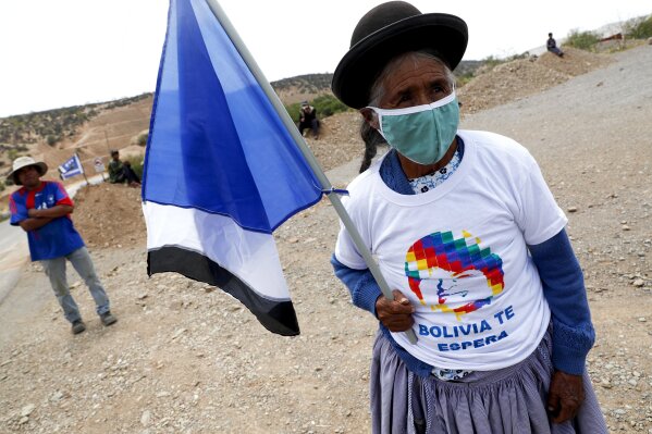 A supporter of Bolivia's former President Evo Morales waits on the roadside for Morales to pass in a caravan near Charajas, Bolivia, Monday, Nov. 9, 2020. Morales, who fled into exile in neighboring Argentina after resigning last November, returned to his homeland the day after the presidential inauguration of his former finance minister Luis Arce. (AP Photo/Juan Karita)