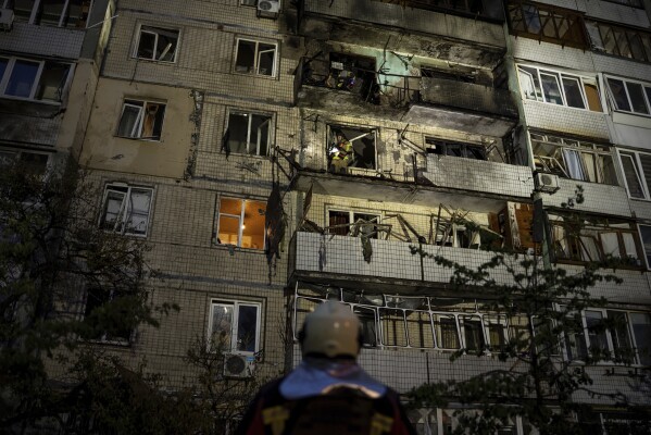Emergency workers navigates his colleagues at the site of residential building damaged after a Russian attack in Kyiv, Ukraine, Saturday, May 24, 2025. (AP Photo/Alex Babenko)