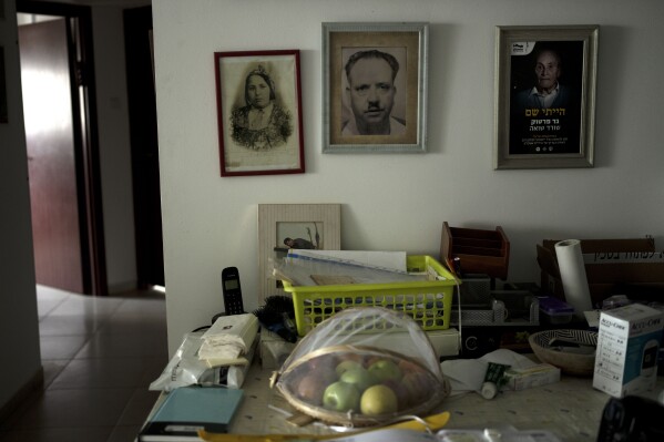 Pictures, left, of the parents of Gad Partok, 93, a Tunisian-born Holocaust survivor, are seen in the frame at right in his home in Ashkelon, southern Israel, Friday, Jan. 26, 2024. (AP Photo/Maya Alleruzzo)