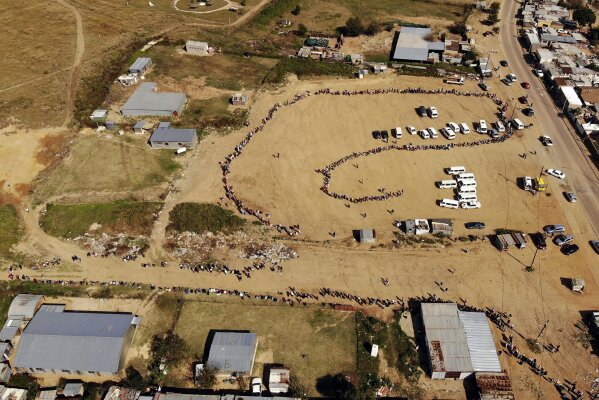 Thousands line up to receive food handouts in the Olievenhoutbos township of Midrand, South Africa, Saturday May 2, 2020. though South Africa begun a phased easing of its strict lockdown measures on May 1, its confirmed cases of coronavirus continue to increase. (AP Photo/Jerome Delay)