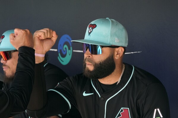 Arizona Diamondbacks' Emmanuel Rivera gets a fist-bump from a teammate in the dugout prior to a spring training baseball game against the Milwaukee Brewers, Sunday, March 3, 2024, in Scottsdale, Ariz. (AP Photo/Ross D. Franklin)