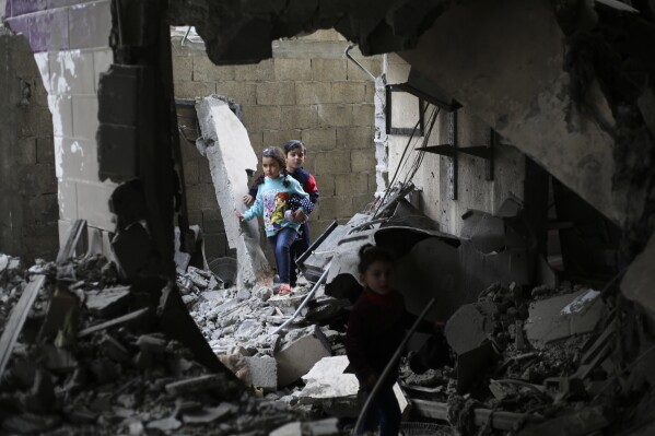 Palestinian children walk after an Israeli strike on residential buildings in Rafah, Gaza Strip, on Thursday, Dec. 14, 2023. (AP Photo/Hatem Ali)
