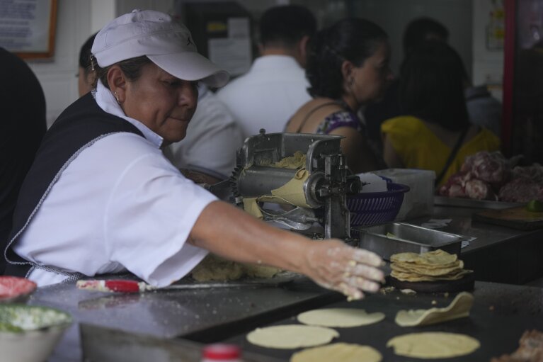 Ein Mitarbeiter wirft Tortillas auf eine Grillplatte an einem Taco-Stand, Tacos El Califa de León, in Mexiko-Stadt, Mittwoch, 15. Mai 2024. Tacos El Califa de León ist der erste Taco-Stand überhaupt, der vom französischen Lebensmittelführer einen Michelin-Stern erhalten hat .  (AP Photo/Fernando Llano)