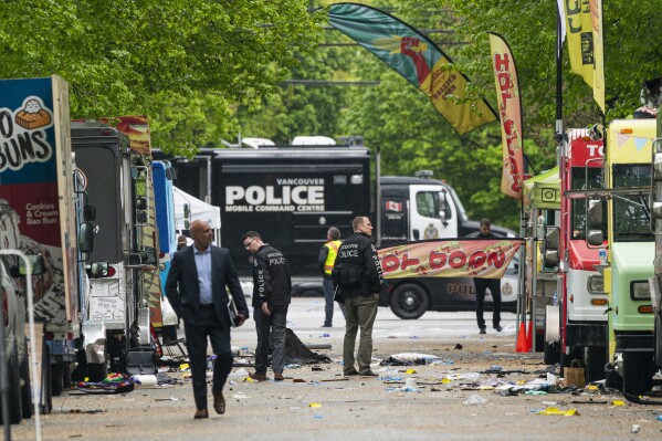Vancouver Police detectives walk along where a car drove through a crowd killing multiple people on the weekend in Vancouver, British Columbia, Monday April 28, 2025. (Rich Lam/The Canadian Press via AP)
