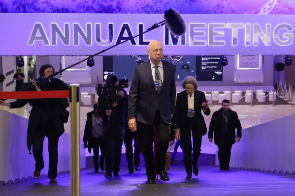 
              Followed by a television team and assistants Klaus Schwab, center, founder and Executive Chairman of the World Economic Forum, walks through the meeting's conference center in Davos, Switzerland, Sunday, Jan. 21, 2018. The meeting brings together entrepreneurs, scientists, chief executives and political leaders from Jan. 23 to 26. (AP Photo/Markus Schreiber)
            