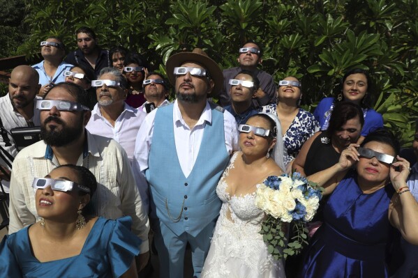 Groom Isaac Medina, center, and bride Jazmin Gonzalez, watch an annular solar eclipse, better known as a ring of fire, before the start of their wedding ceremony, in Merida, Mexico, Oct. 14, 2023. (AP Photo/Martin Zetina, File)