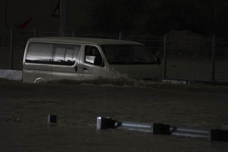 A van drives through standing water in Dubai, United Arab Emirates, Tuesday, April 16, 2024. Heavy rain lashed the United Arab Emirates on Tuesday, flooding parts of major highways and leaving vehicles abandoned on Dubai's roads.  Meanwhile, the death toll from heavy flooding in neighboring Oman rose to 18 and others remain missing as the sultanate braced for the storm.  (AP Photo/Jon Gambrell)