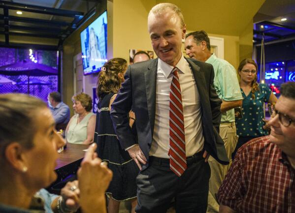 GOP attorney general candidate Jim Schultz thanks supporters Annie Paruccini and Dan Wolter at Moe's Burger in St. Paul, Minn., on Tuesday, Aug. 9, 2022. In the background is his wife, Molly. (Richard Tsong-Taatarii/Star Tribune via AP)