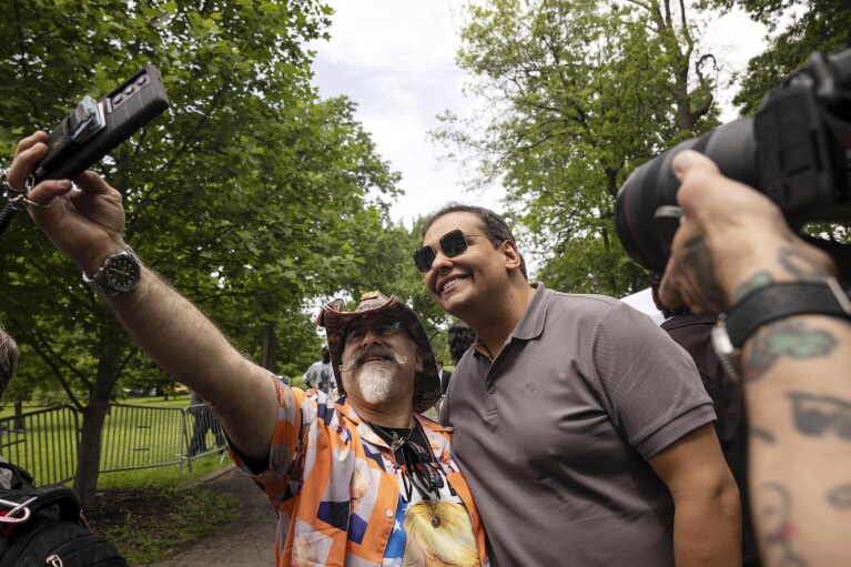 Former Rep. George Santos, right, takes pictures with supporters outside a campaign rally for Republican presidential candidate former President Donald Trump in the Bronx borough of New York, Thursday, May. 23, 2024. (AP Photo/Yuki Iwamura)