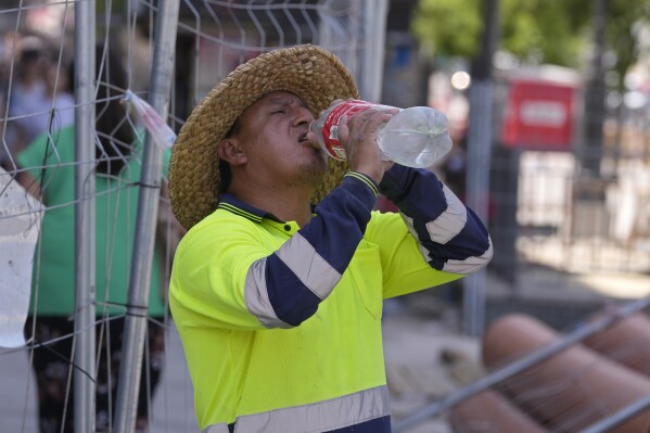 FILE - A road worker stops to take a drink of water in Madrid, Spain, Monday, July 18, 2022. The U.N. labor organization warned Monday, April 22, 2024, that over 70% of the world's workforce is likely to be exposed to excessive heat during their careers, citing increased concern about exposure to sunlight. It also warned of air pollution, pesticides and other hazards that could lead to health problems, including cancer. (AP Photo/Paul White, File)