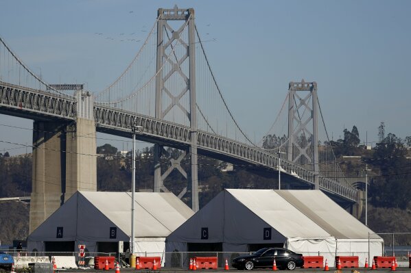 Tents from a COVID-19 testing site sit in front of the San Francisco-Oakland Bay Bridge during the coronavirus outbreak in San Francisco, Monday, Nov. 16, 2020. (AP Photo/Jeff Chiu)