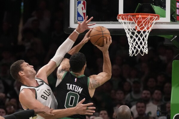 Milwaukee Bucks center Brook Lopez, left, tries to block Boston Celtics forward Jayson Tatum (0) during the second half of an NBA basketball game, Wednesday, Nov. 22, 2023, in Boston. (AP Photo/Charles Krupa)