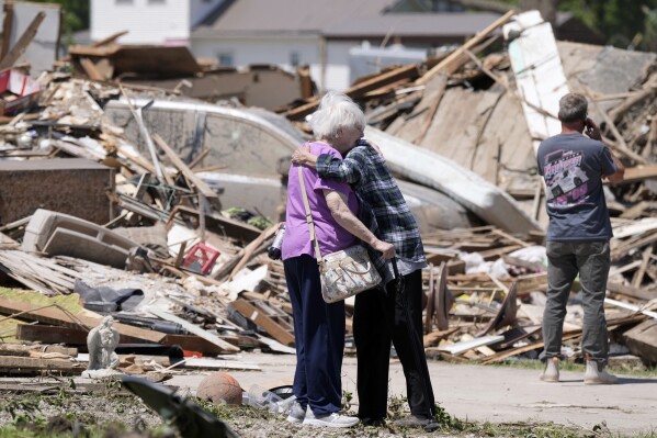 Joan Mitchell (izquierda) recibe el abrazo de su vecina Edith Schaecher frente a sus casas, destrozadas por un tornado, el 23 de mayo de 2024, en Greenfield, Iowa. (AP Foto/Charlie Neibergall)