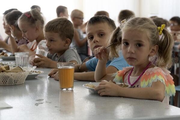 Children from an orphanage in the Donetsk region, eat a meal at a camp in Zolotaya Kosa, the settlement on the Sea of Azov, Rostov region, southwestern Russia, Friday, July 8, 2022. Russia's open effort to adopt Ukrainian children and bring them up as Russian is emerging as one of the most explosive issues of the war. (AP Photo)