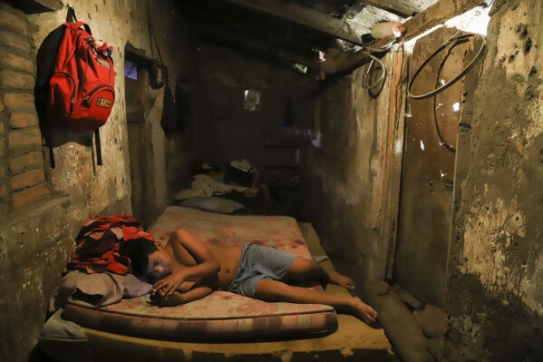 Cesar Velasquez, 14, lies on a mattress, while spending time with his cell phone, at his grandmother's house where he now lives, because his parents were detained during the government's crackdown on its war against drugs, in Santa Ana, El Salvador, Wednesday, Jan. 31, 2024.  (AP Photo/Salvador Melendez)