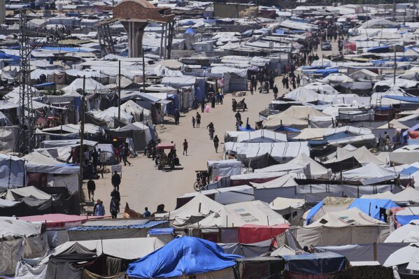 Displaced Palestinians walk through a makeshift tent camp in the Muwasi area of Khan Younis, in the Gaza Strip, on Monday, May 5, 2025. (AP Photo/Abdel Kareem Hana)