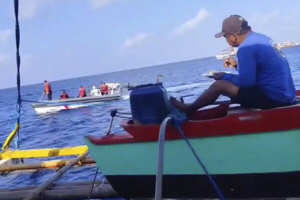 CAPTION CORRECTS YEAR In this photo taken from video provided by Joely Saligan, Chinese coast guard on rubber boats passes by a Philippine fishing boat at the disputed Scarborough Shoal off the northwestern Philippines on Jan. 12, 2024. A Filipino fishing boat captain said Tuesday that he asserted Philippine sovereign rights in a tense confrontation with Chinese authorities in the disputed South China Sea in a new spat that is testing efforts by Beijing and Manila to deescalate tensions in a potential Asian flashpoint. (Joely Saligan via AP)