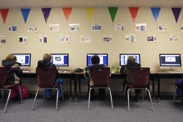 FILE - Watford City Elementary School students use computers in a portable building in Watford City, N.D., Dec. 17, 2014. The North Dakota Senate passed a series of bills Monday, April 3, 2023, that would restrict transgender people's rights in schools, sports, health care, workplaces and daily life. (AP Photo/Eric Gay, File)