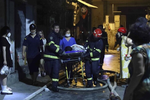 Rescue workers carry a person on stretcher out of a building on fire in Hanoi, Vietnam Wednesday, Sept. 13, 2023. Authorities said "many" people had been killed after a fire broke out in the apartment block. (Pham Trung Kien/ VNA via AP)