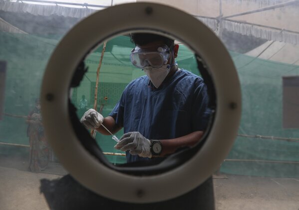 A health worker collects nasal swab samples at a COVID-19 testing center in  Hyderabad, India, Monday, April 12, 2021. With its explosive surge in recent days, India's confirmed infections surpassed Brazil's total Monday as the second-worst hit country. (AP Photo/Mahesh Kumar A.)