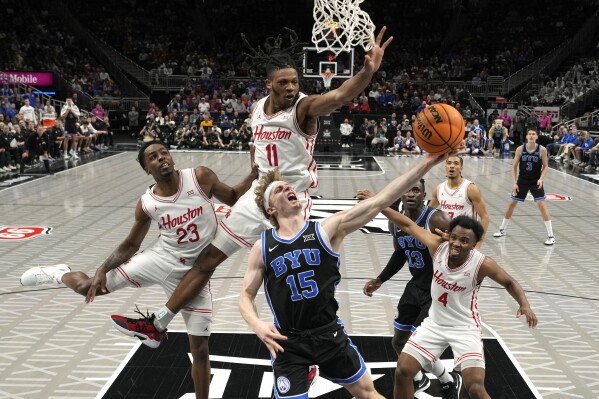 Brigham Young's Richie Saunders (15) shoots as Houston's Terrance Arceneaux (23), Joseph Tugler (11) and L.J. Cryer (4) defend during the first half of an NCAA college basketball game in the semifinal round of the Big 12 Conference tournament, Friday, March 14, 2025, in Kansas City, Mo. (AP Photo/Charlie Riedel)