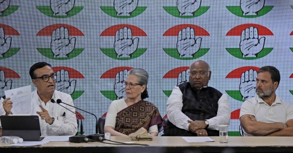 Congress party treasurer Ajay Maken, left, speaks and displays the notice from Indian taxation authority as party president Mallikarjun Kharge, second right, and senior party leaders Sonia Gandhi, second left, and Rahul Gandhi listen during a press conference at their party headquarters in New Delhi, India, Thursday, March 21, 2024. (AP Photo/Manish Swarup)