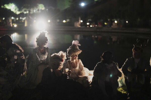 Costumed guests take a break as they attend the Great Masked Ball in the Orangerie of the Versailles castle, outside Paris, Sunday, June 22, 2025. (AP Photo/Christophe Ena)