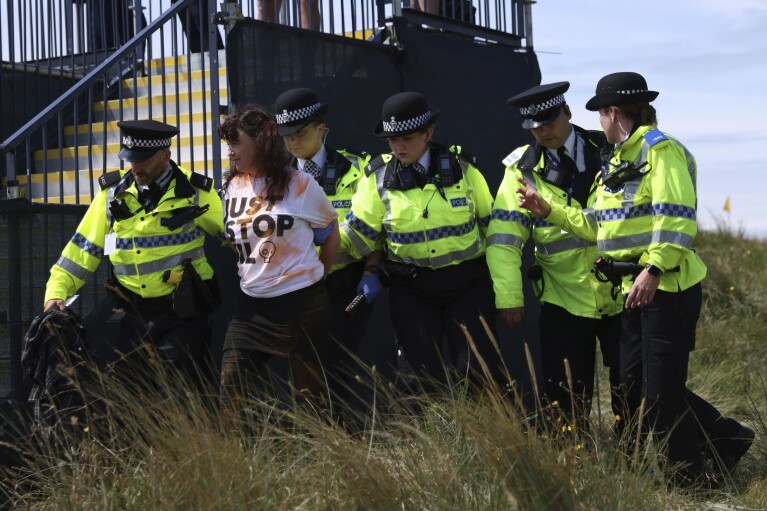 A Just Stop Oil protester is led away by police and security near the 17th hole during the second day of the British Open Golf Championships at the Royal Liverpool Golf Club in Hoylake, England, July 21, 2023. (AP Photo/Peter Morrison, File)