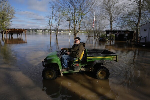 Dale Bardes, the oldest resident of Rabbit Hash, Ky., drives on the edge of the rising Ohio River floodwaters as he checks the water levels near the Rabbit Hash General Store on Lower River Road, Monday, April 7, 2025, in Rabbit Hash, Ky. (AP Photo/Carolyn Kaster)
