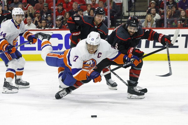 Carolina Hurricanes' Jalen Chatfield (5) battles with New York Islanders' Anders Lee (27) for the puck during the first period in Game 5 of an NHL hockey Stanley Cup first-round playoff series in Raleigh, N.C., Tuesday, April 30, 2024. (AP Photo/Karl B DeBlaker)