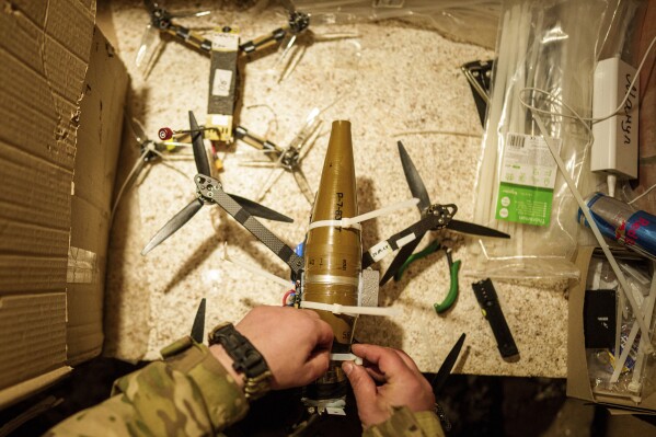 Um soldado ucraniano do Batalhão de Aquiles da 92ª Brigada atribui munição a um drone suicida antes de um vôo sobre posições russas na região de Kharkiv, na Ucrânia, no domingo, 12 de maio de 2024. (AP Photo/Evgeniy Maloletka)