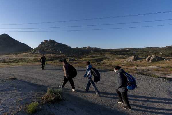 Migrants follow a U.S Border Patrol agent to be processed after crossing the border with Mexico Wednesday, May 8, 2024, near Jacumba Hot Springs, Calif. San Diego became the busiest corridor for illegal crossings in April, according to U.S. figures, the fifth region to hold that title in two years in a sign of how quickly migration routes are changing. (AP Photo/Ryan Sun)