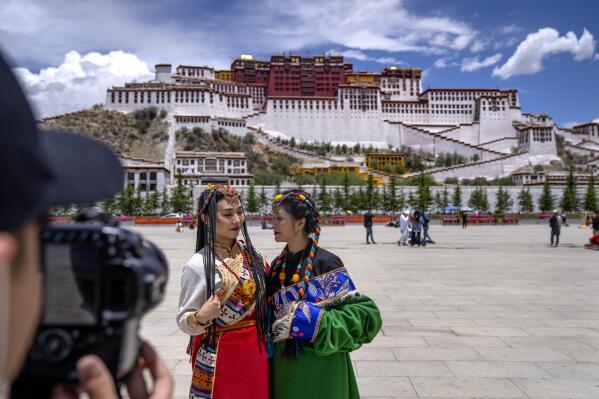 Chinese tourists in Tibetan dress pose for a photo at a square near the Potala Palace in Lhasa in western China's Tibet Autonomous Region, Tuesday, June 1, 2021. Tourism is booming in Tibet as more Chinese travel in-country because of the coronavirus pandemic, posing risks to the region's fragile environment and historic sites. (AP Photo/Mark Schiefelbein)