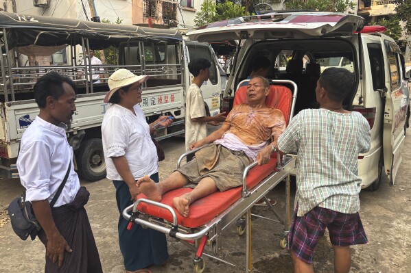 Rescue workers take an injured man who was trapped under a building Friday, March 28, 2025, in Naypyitaw, Myanmar. (AP Photo/Aung Shine Oo)