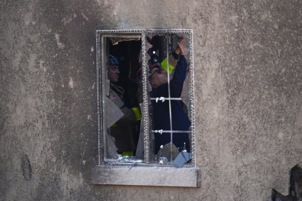 Firefighters inspect the inside of a home that was damaged when a small plane crashed into a San Diego neighborhood, setting several homes on fire and forcing evacuations along several blocks early Thursday, May 22, 2025. (AP Photo/Gregory Bull)