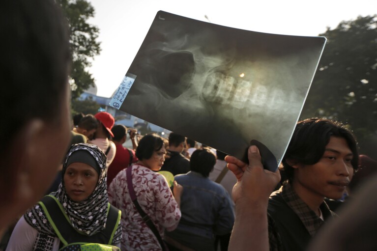 FILE - A man watches a solar eclipse through an x-ray film in Jakarta, Indonesia, Wednesday, March 9, 2016. (AP Photo/Dita Alangkara, File)